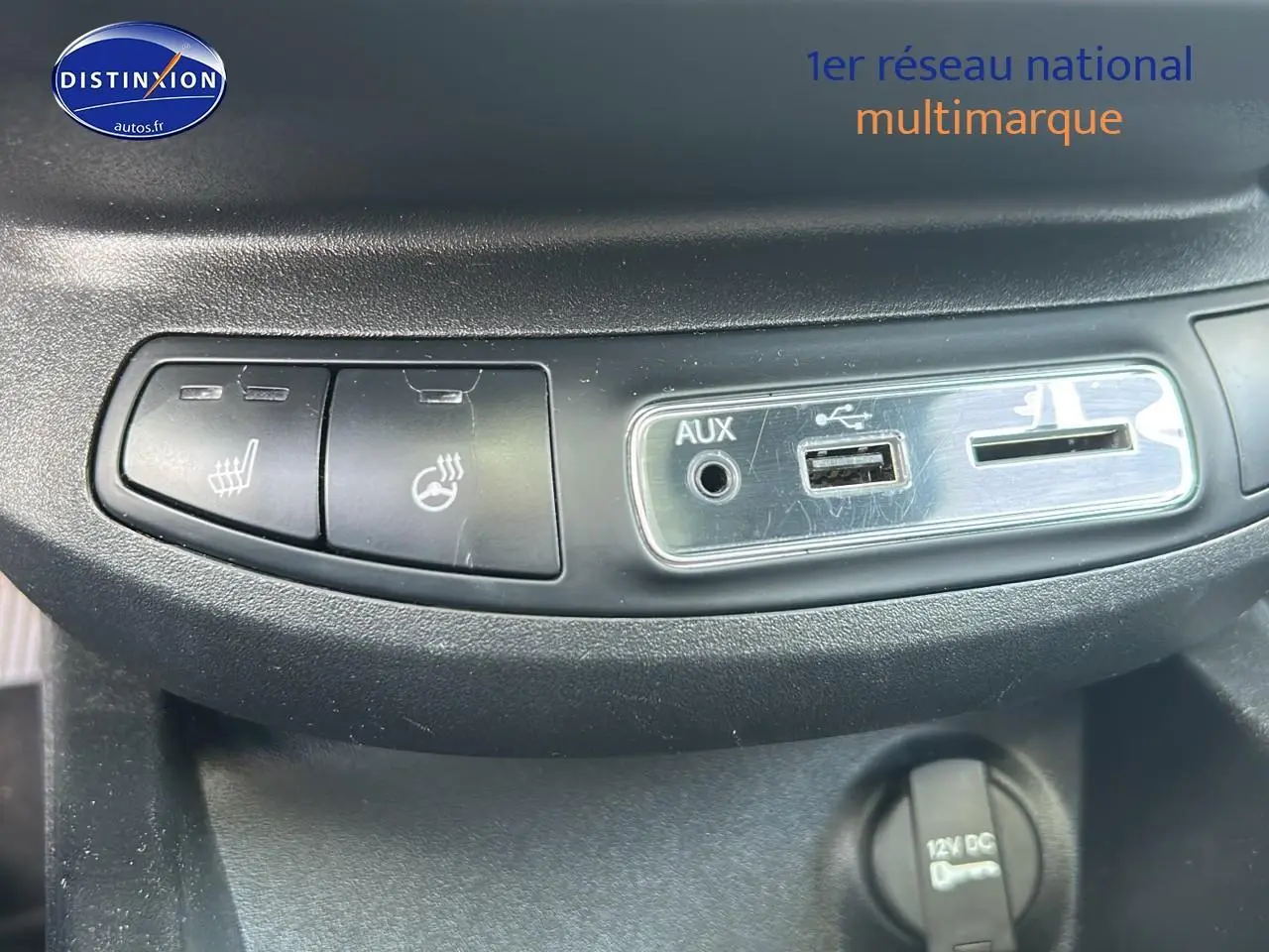 Gros plan sur les commandes de chauffage de siège et les prises AUX, USB et 12V du tableau de bord d'une Fiat 500X rouge.