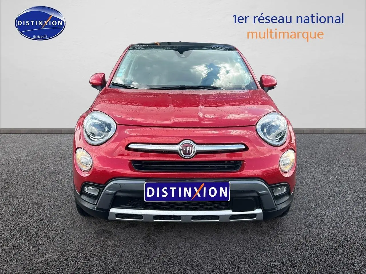 Vue frontale d'une FIAT 500X rouge 2016 avec bouclier noir et calandre chromée sur sol goudronné.