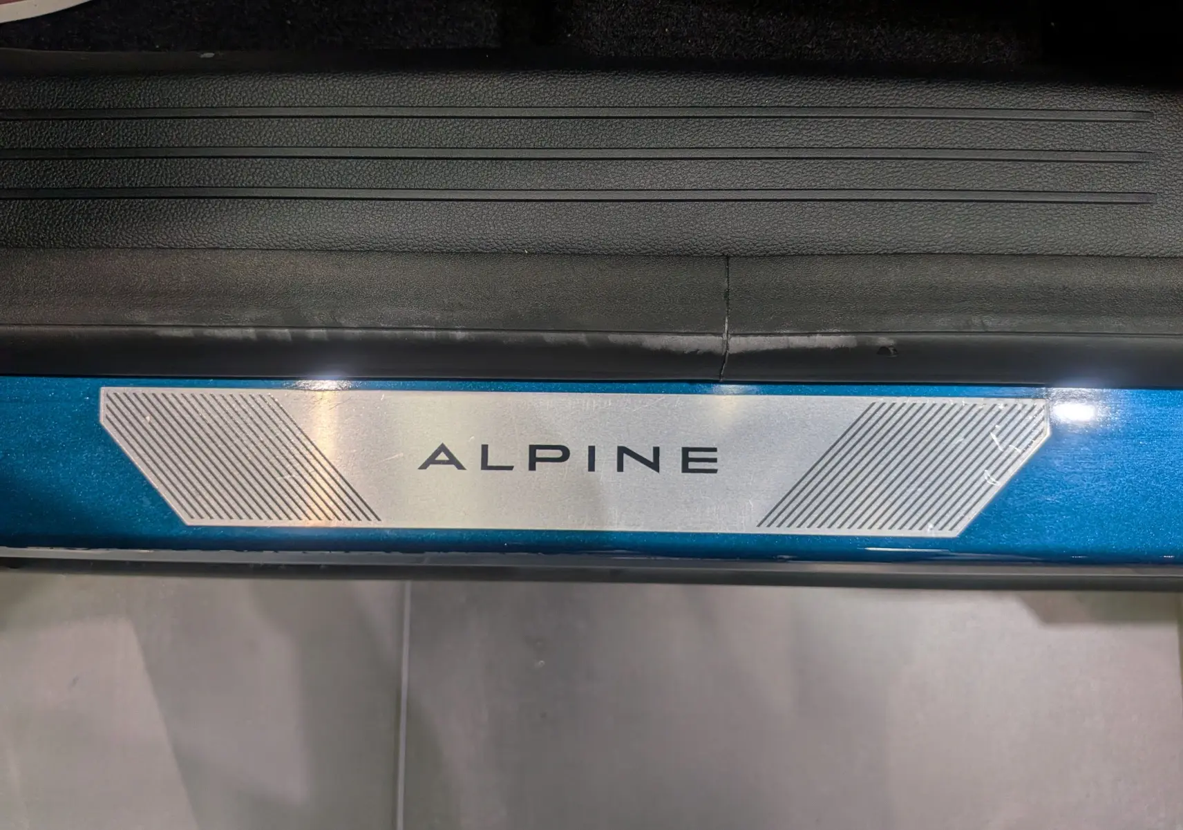 Gros plan sur la plaque de seuil de porte bleu outremer avec l'inscription Alpine du Renault Austral E-Tech 2025.
