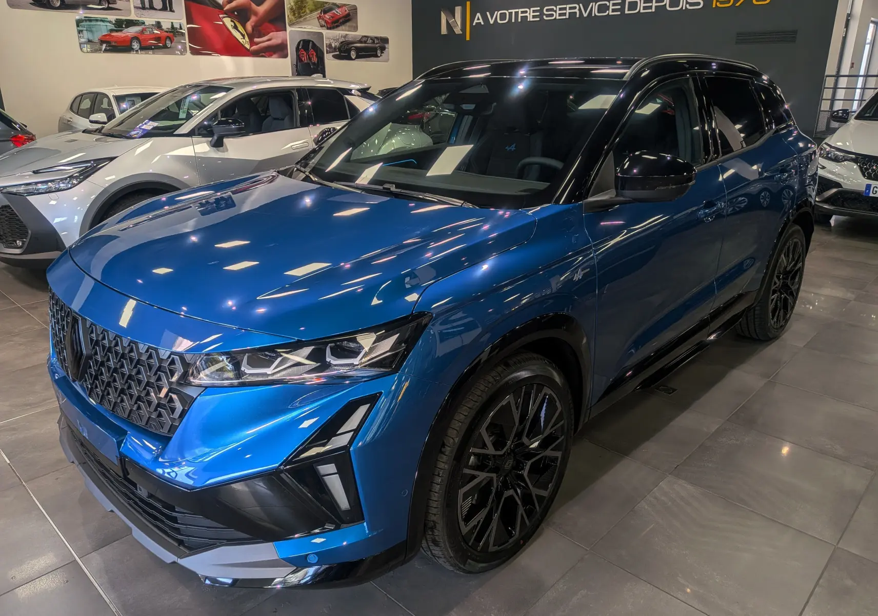 Renault Austral 2025 full hybride bleu outremer avec toit noir, vue 3/4 avant droit en showroom lumineux.