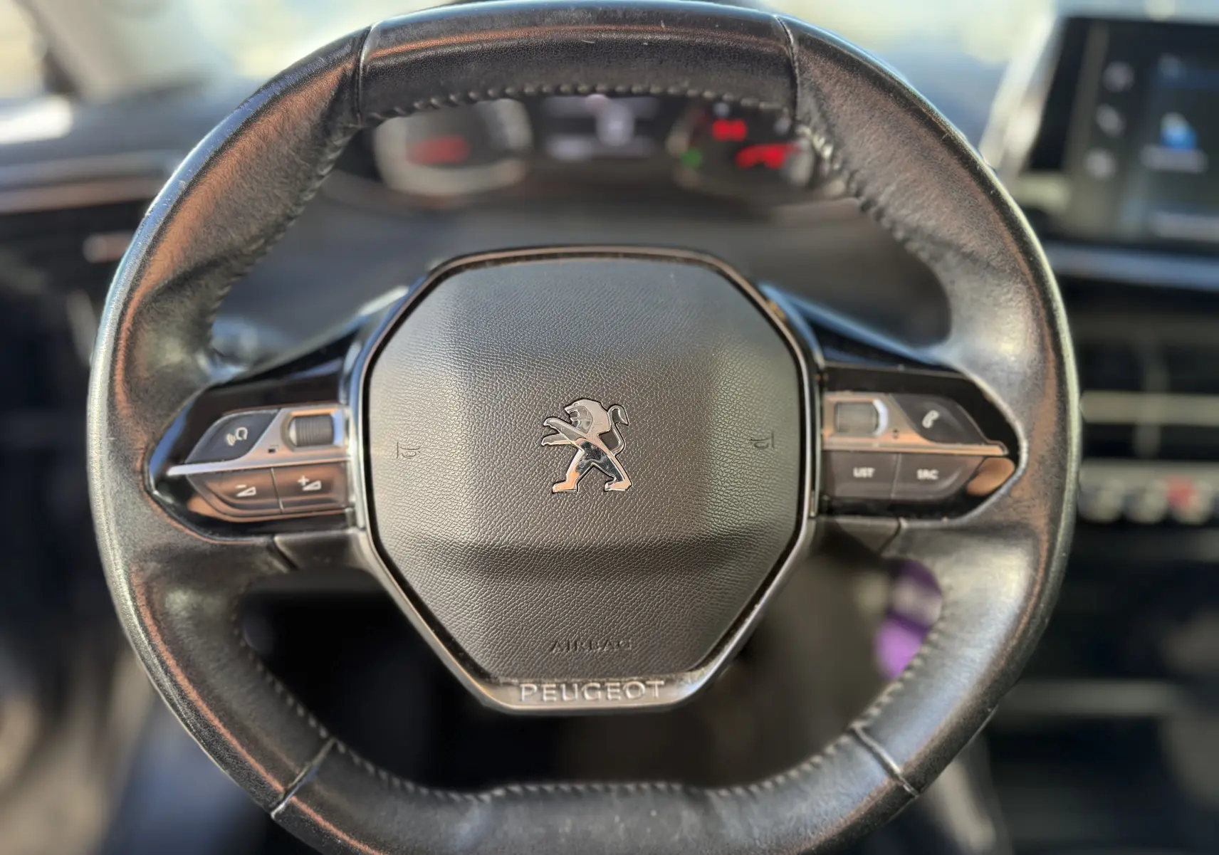 Volant en cuir noir de Peugeot 2008 1.5 HDi 100 Active 2020 avec commandes intégrées et logo lion central.