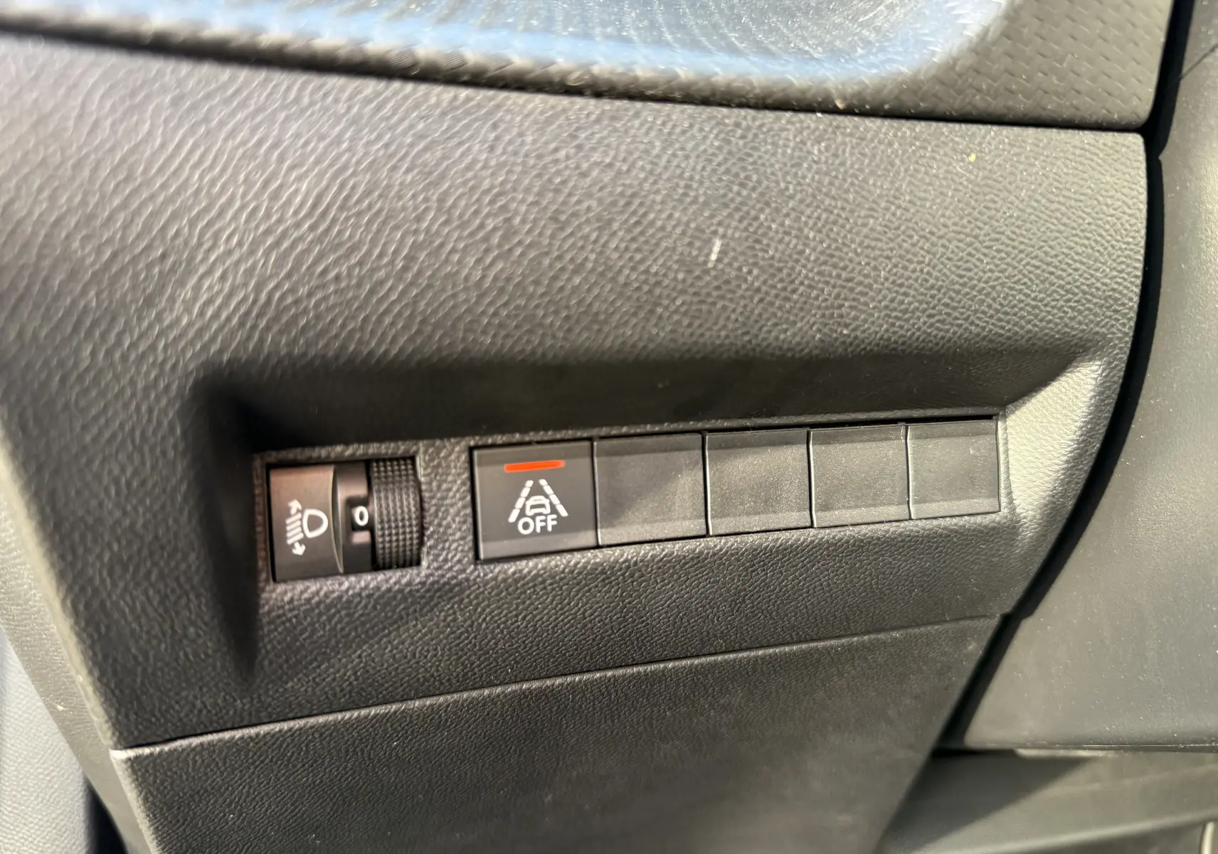 Gros plan sur les commandes de réglage des phares et désactivation de l'alerte de franchissement de ligne dans une Peugeot 2008.
