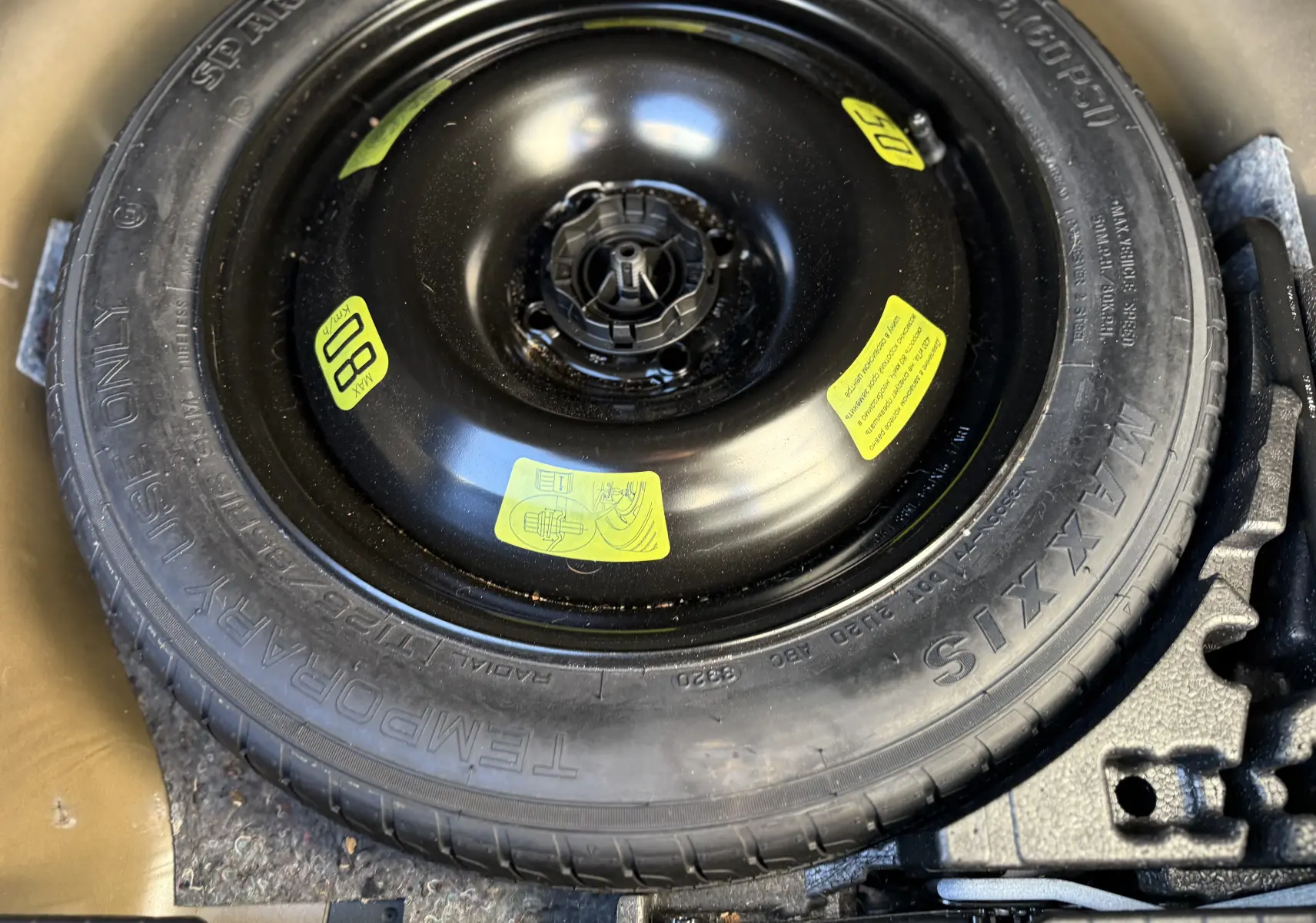 Gros plan sur la roue de secours noire Maxxis dans le coffre d'un Peugeot 2008 gris 1.5 HDI 2020.