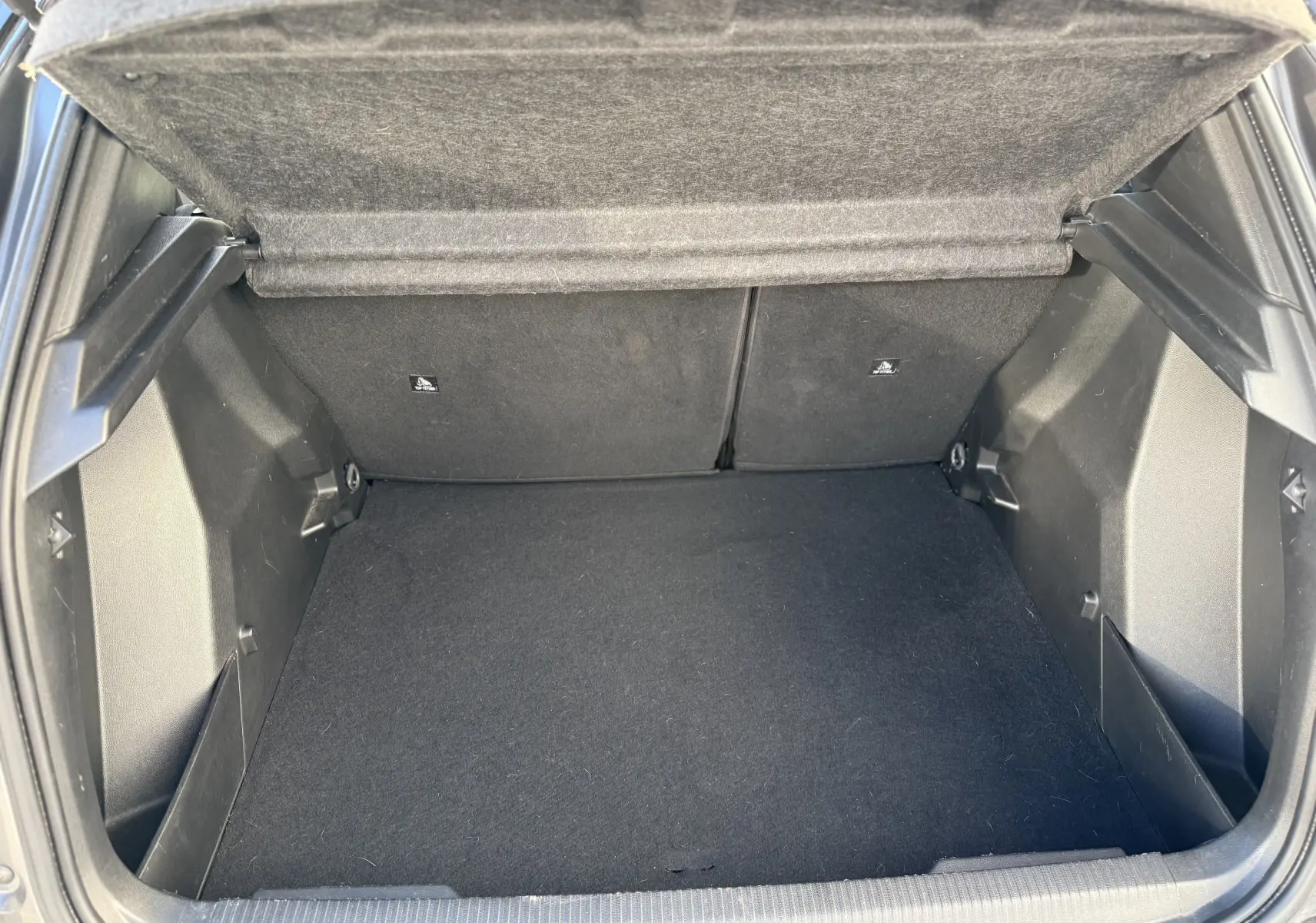 Coffre ouvert vu de l'arrière d'un Peugeot 2008 gris 1.5 HDi 100 Active, montrant un espace de rangement propre et vide.