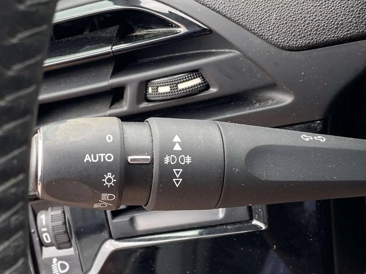 Gros plan sur la commande des feux et clignotants noirs à gauche du volant d'un Citroën C4 Spacetourer 2019.