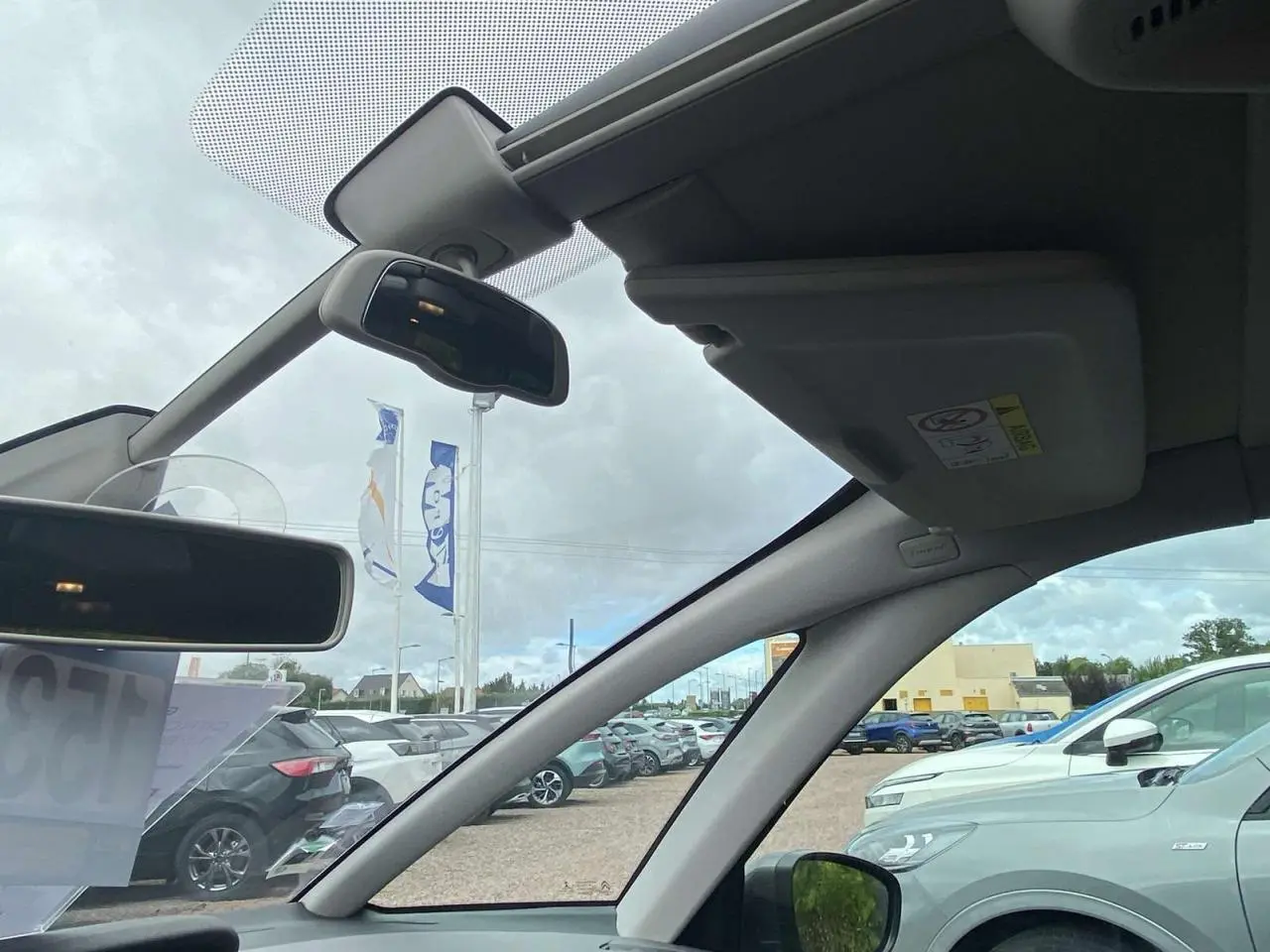 Vue intérieure côté conducteur du pare-brise et rétroviseurs d'un Citroën C4 Spacetourer 2019, ciel nuageux visible.