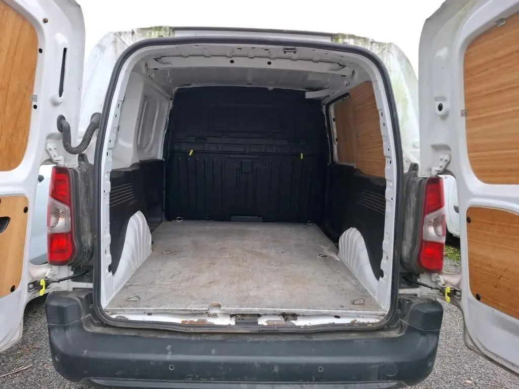 Vue arrière ouverte du Peugeot Partner blanc 2020, montrant l'espace de chargement vide avec habillage bois sur les portes.
