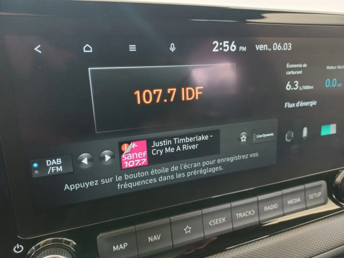 Écran tactile central du tableau de bord du Hyundai Kona gris foncé, affichant radio et données de consommation.