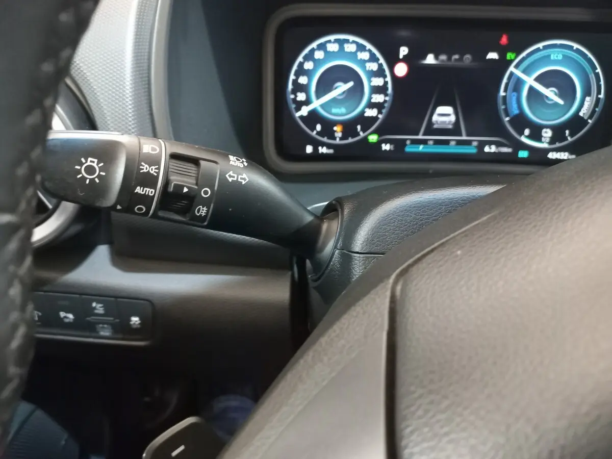 Vue rapprochée du tableau de bord numérique et du commodo d'éclairage du Hyundai Kona hybride 2022, intérieur noir.