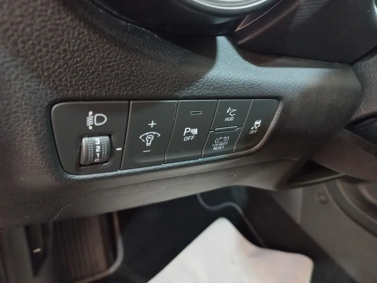 Gros plan sur les commandes de réglage des phares et aides à la conduite côté conducteur du Hyundai Kona gris foncé 2022.