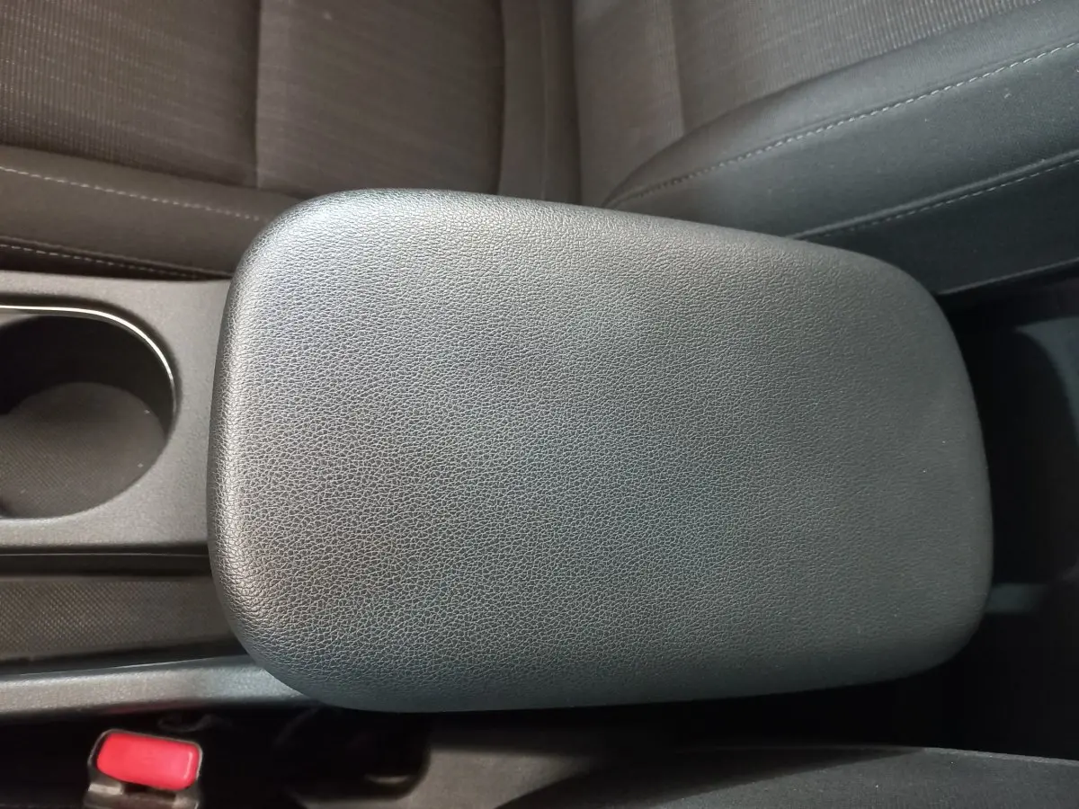 Gros plan sur l'accoudoir central en cuir noir et porte-gobelet intérieur du Hyundai Kona gris foncé 2022.