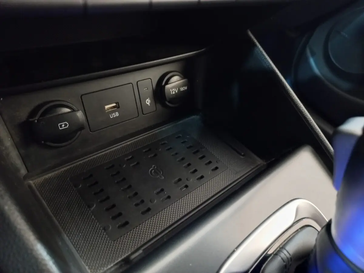 Gros plan sur la console centrale du Hyundai Kona gris foncé montrant prises USB, 12V et recharge sans fil.