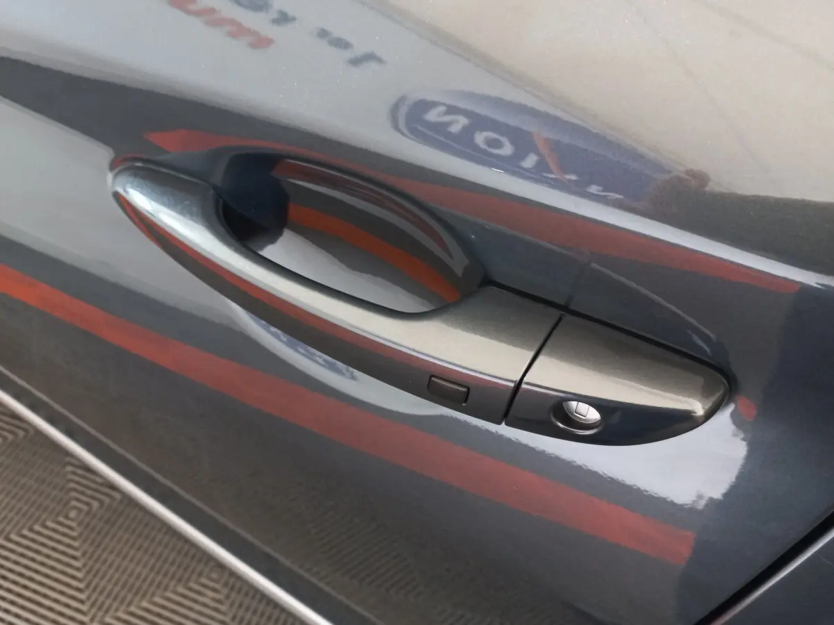 Poignée de porte côté gauche gris foncé du Hyundai Kona 2022, avec bouton de déverrouillage intégré.