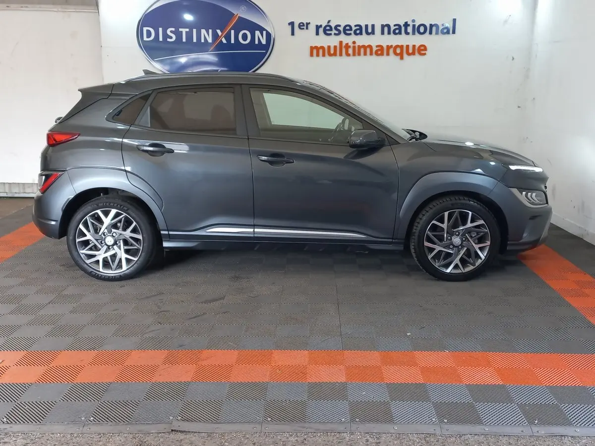 Vue de profil côté gauche d'un Hyundai Kona gris foncé 2022 avec jantes alliage et vitres teintées.