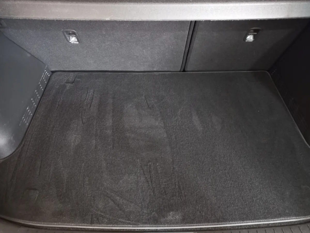 Vue plongeante sur le coffre spacieux et propre du Hyundai Kona 1.6 Hybrid 2022, avec tapis de sol noir.