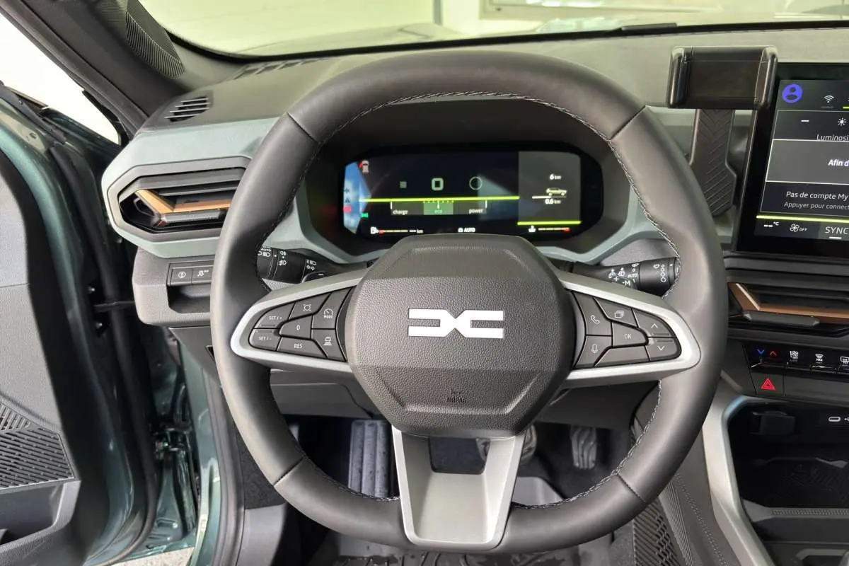 Vue rapprochée du volant cuir noir et du tableau de bord digital du Dacia Bigster vert cèdre, avec commandes intégrées au volant.