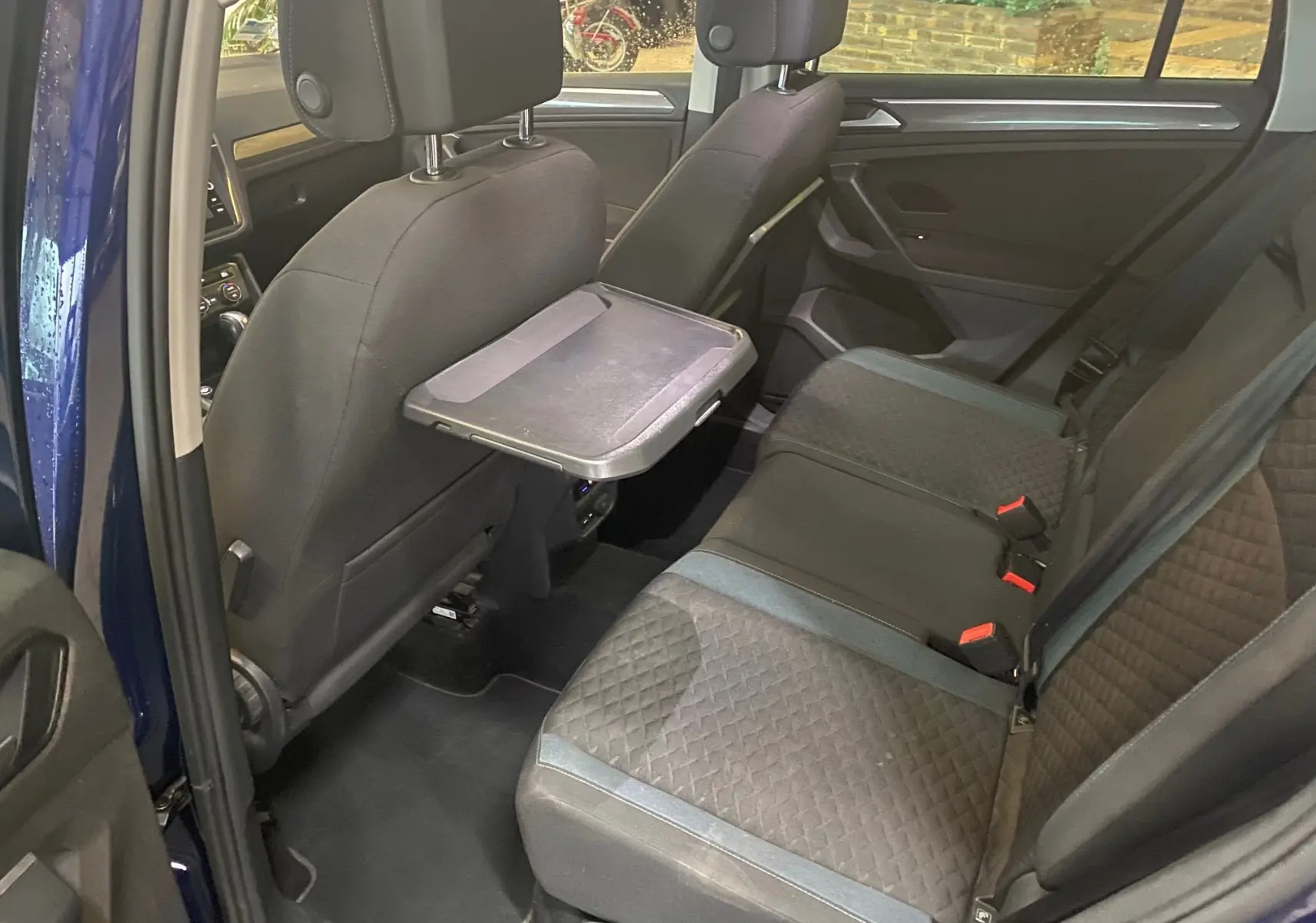 Intérieur arrière du Volkswagen Tiguan bleu vert 2020, vue côté gauche avec tablette rabattable sur siège avant.