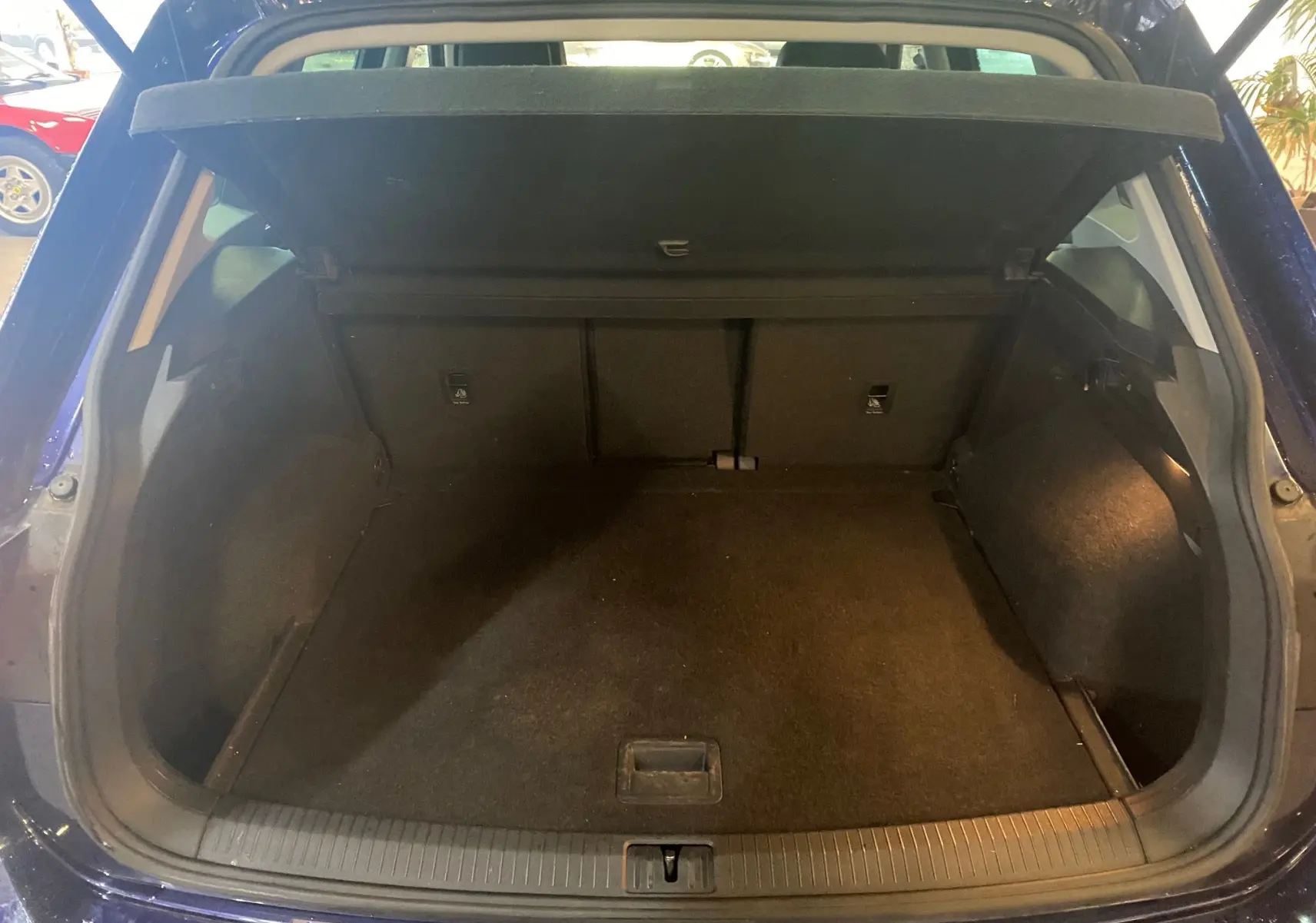 Coffre ouvert vu de l'arrière d'un Volkswagen Tiguan bleu vert 2020, espace de chargement vide et propre.