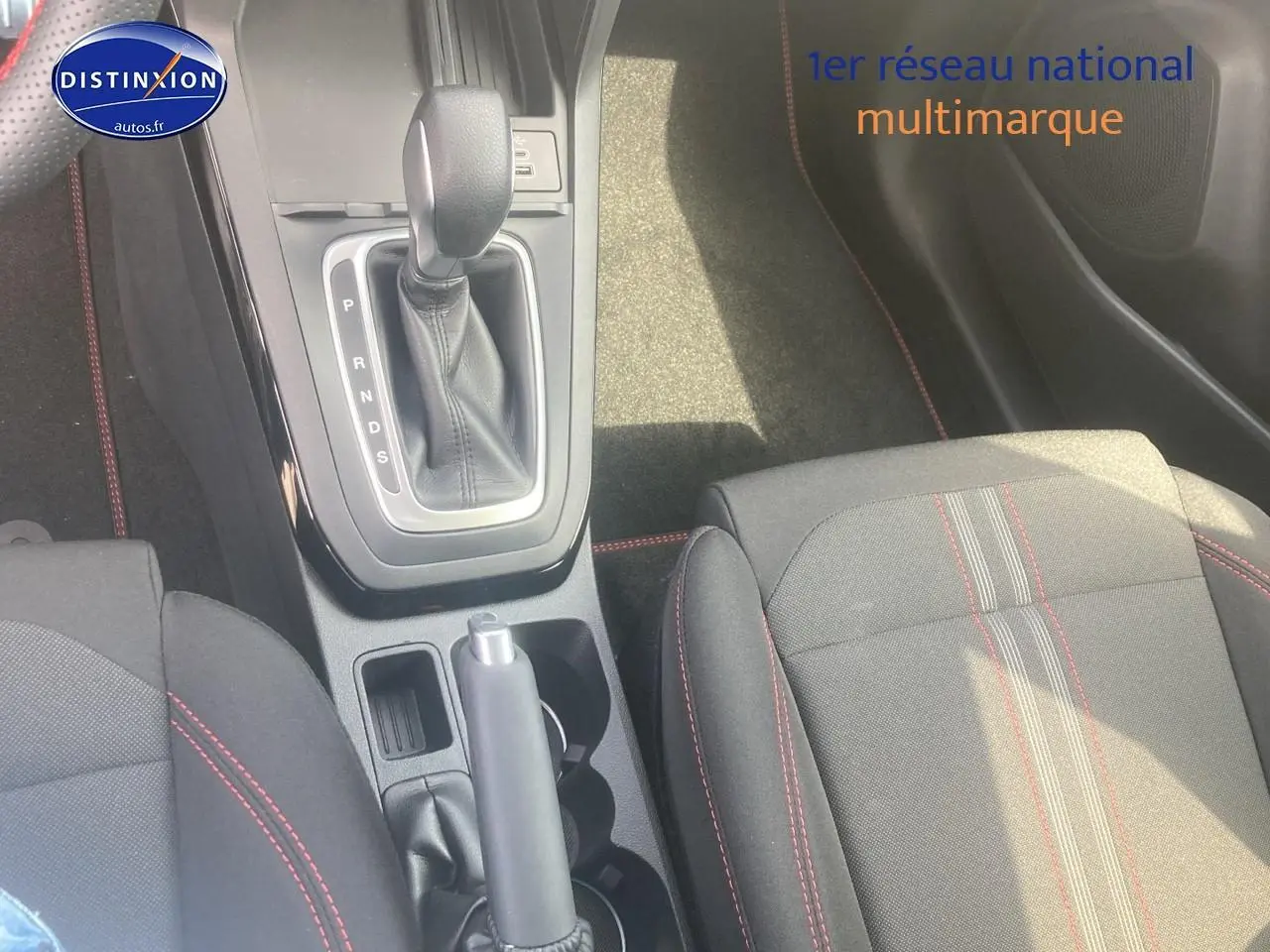 Gros plan sur la console centrale et les sièges tissu gris avec surpiqûres rouges du Ford Puma gris cactus 2025.