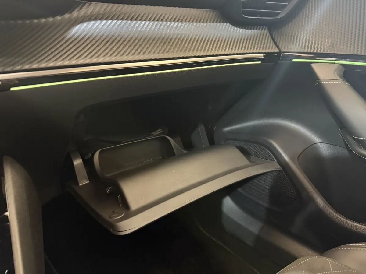 Gros plan sur la boîte à gants ouverte et le tableau de bord noir avec insert décoratif effet carbone du Peugeot 2008 GT Pack.