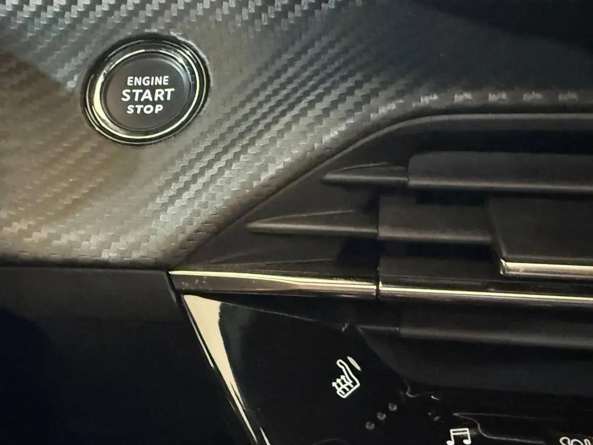 Détail intérieur du tableau de bord noir avec bouton start/stop et commande de siège chauffant du Peugeot 2008 GT Pack 2021.