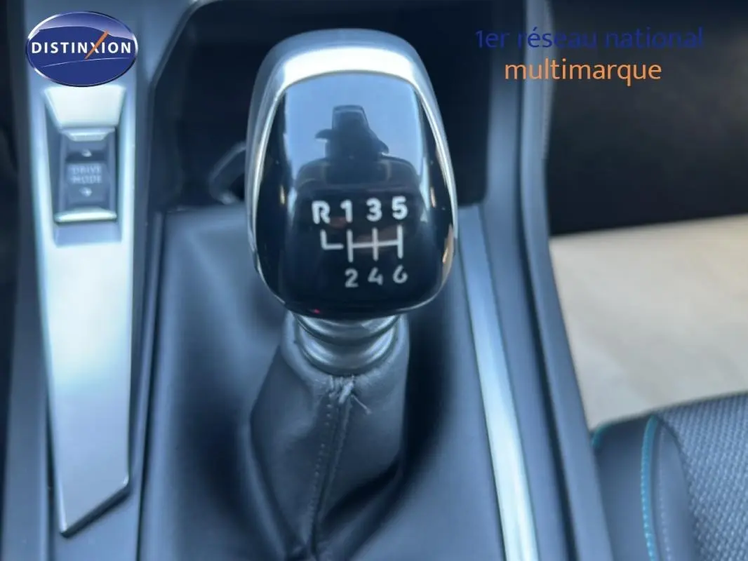 Gros plan sur le levier de vitesse manuel noir de la Peugeot 308 bleu clair, avec console centrale et bouton Drive Mode visible.