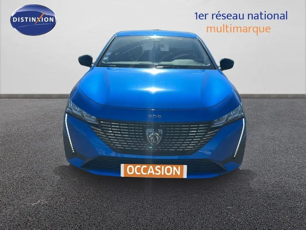 Vue frontale d'une Peugeot 308 bleu clair 2021 avec calandre moderne et feux LED verticaux allumés.