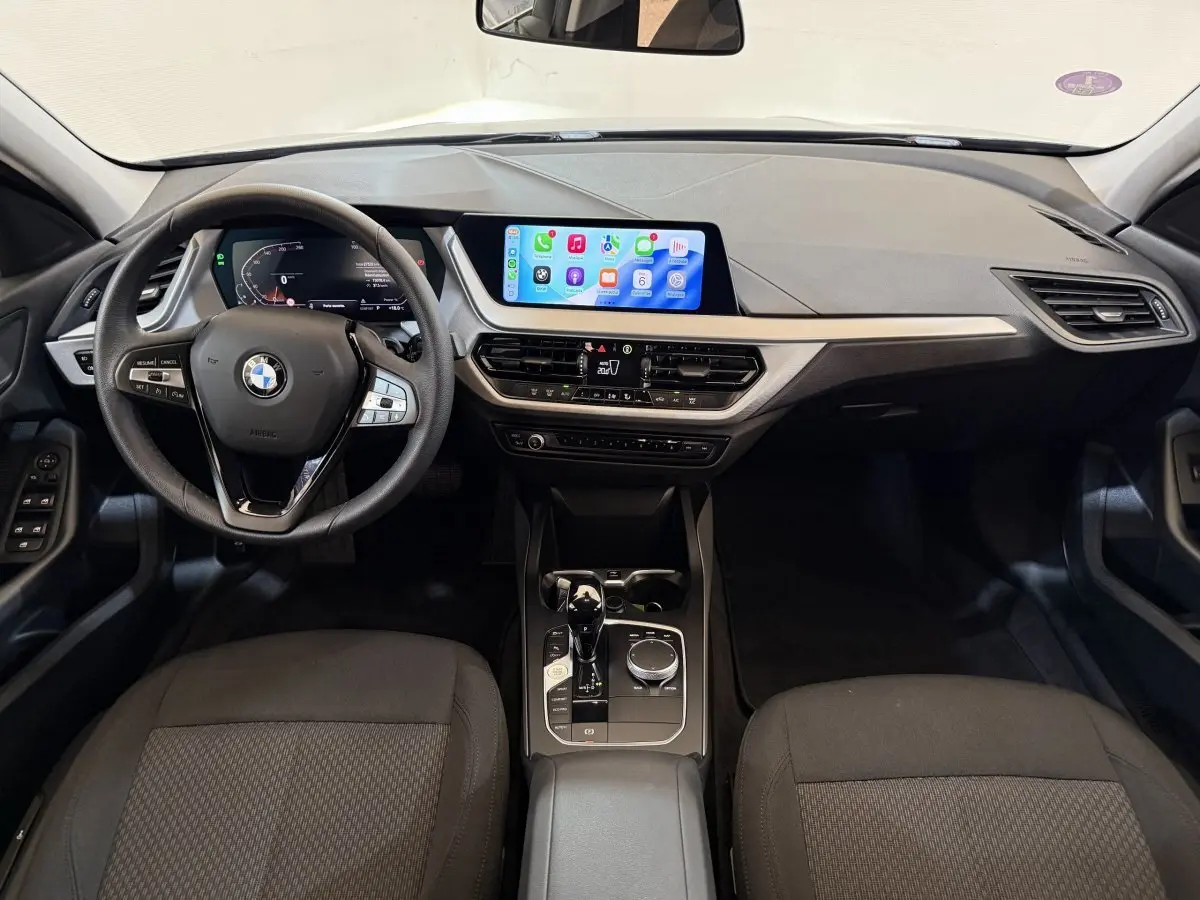 Vue intérieure avant de la BMW Série 1 116i Business Design avec tableau de bord numérique et écran tactile central.