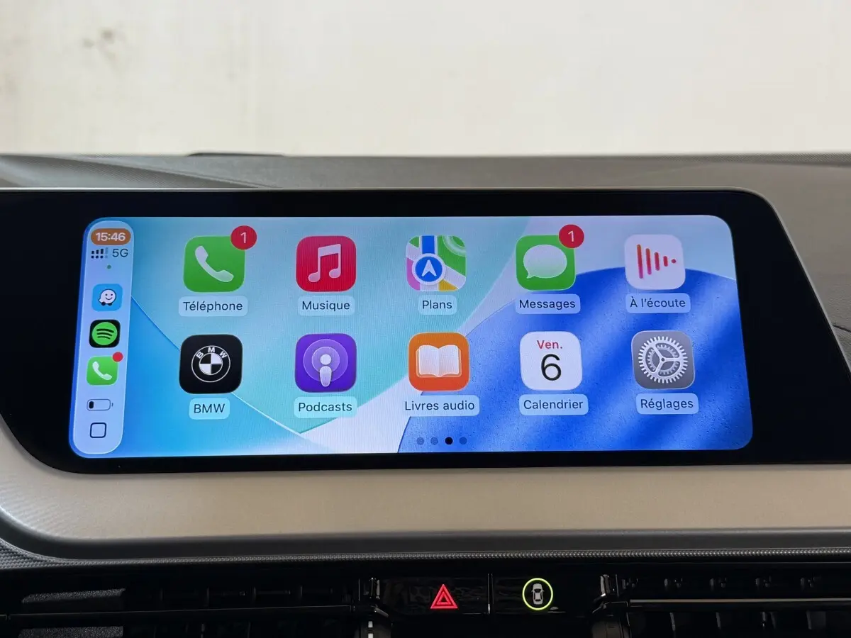 Écran tactile central de la BMW Série 1 116i Business Design 2023 affichant Apple CarPlay en intérieur beige.