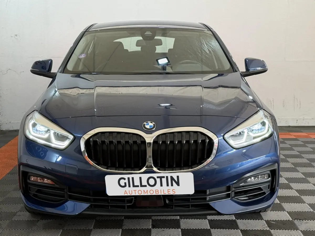 Vue avant d'une BMW Série 1 116i Business Design bleu avec calandre double haricot et phares LED allumés.