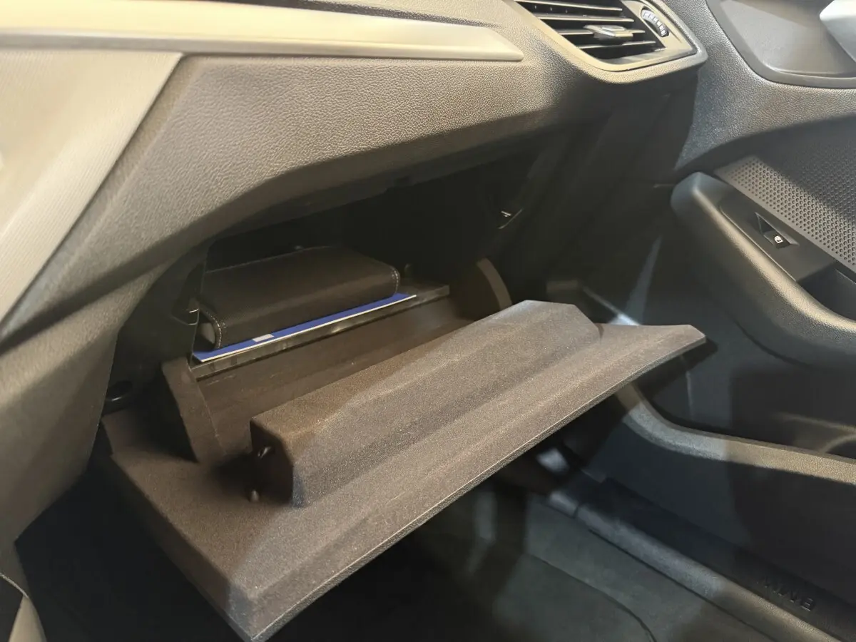 Vue intérieure côté passager de la BMW Série 1 116i Business Design 2023 avec boîte à gants ouverte et rangement visible.