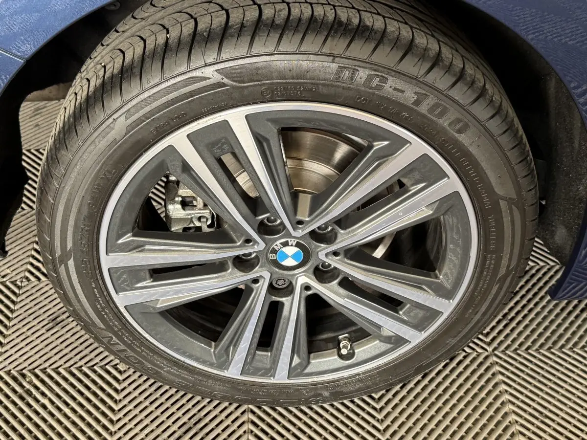 Gros plan sur la jante alliage BMW de la Série 1 bleu, avec logo central et pneu visible.