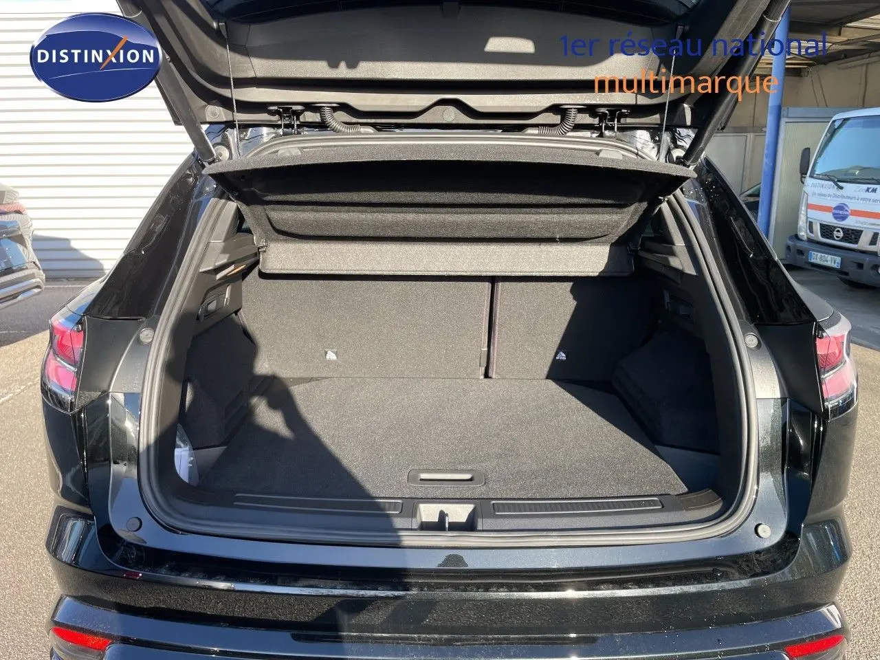 Coffre ouvert vu de l'arrière d'un Renault Austral noir étoile métal, montrant un espace de chargement spacieux et bien fini.