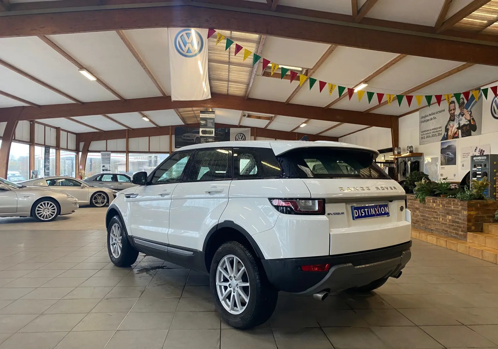 Range Rover Evoque blanc vu en 3/4 arrière droit dans un showroom lumineux avec sol carrelé.