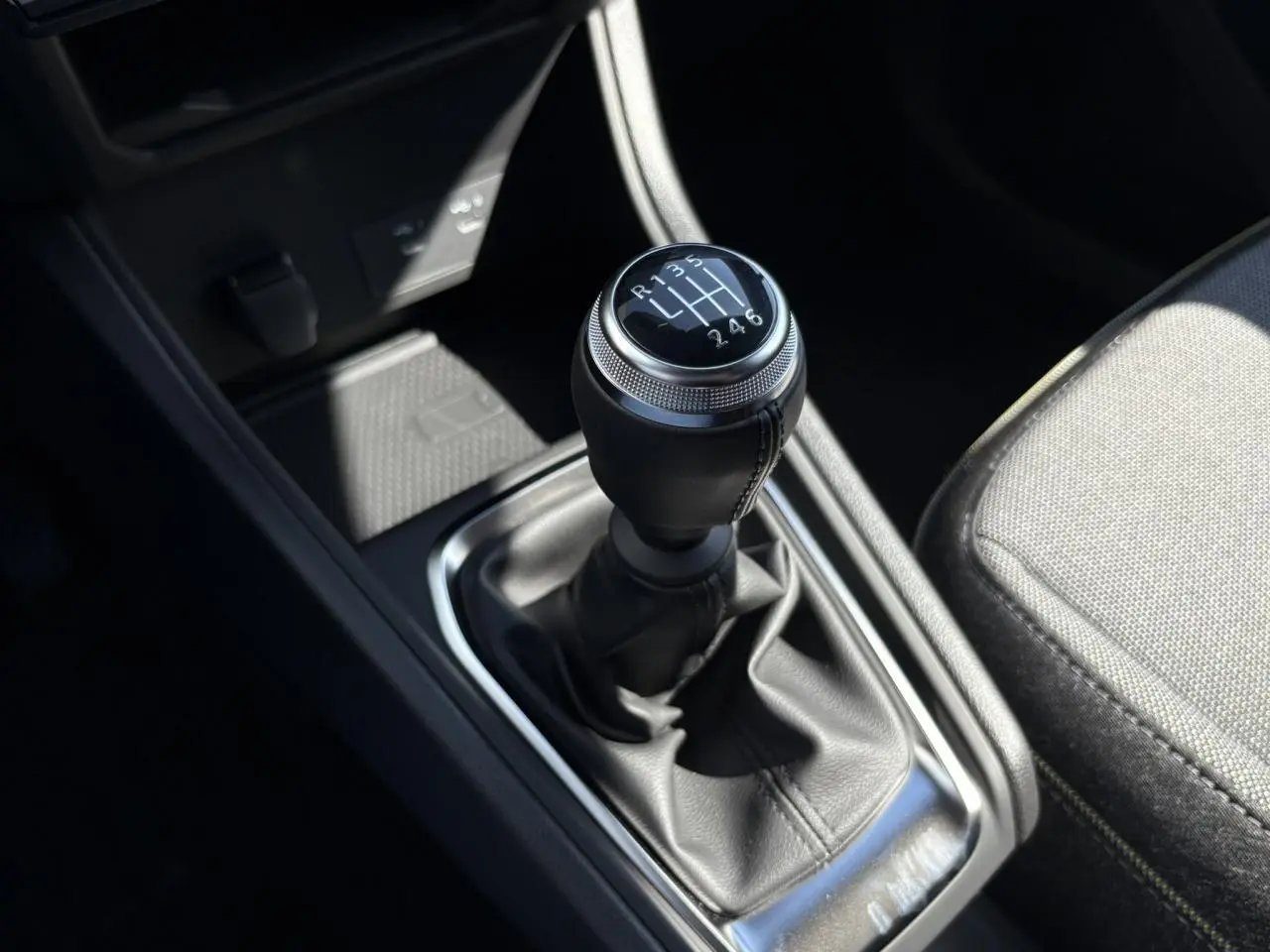 Le levier de vitesses manuel noir du Renault Captur 2025 vu de dessus, avec siège tissu gris à côté.