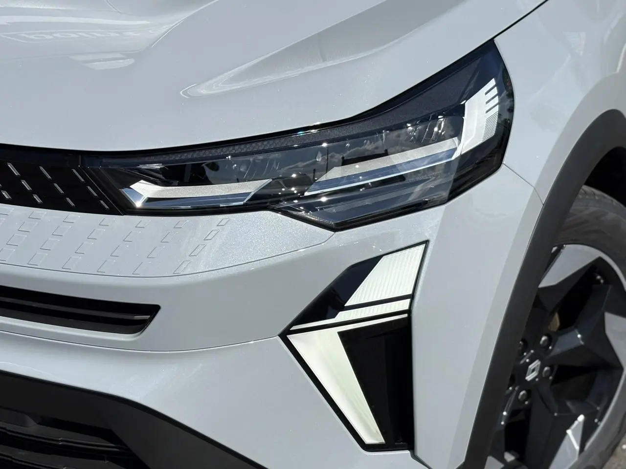 Gros plan sur le phare avant droit et la jante noire du Renault Captur Gris Rafale 2025 avec éclairage LED distinctif.