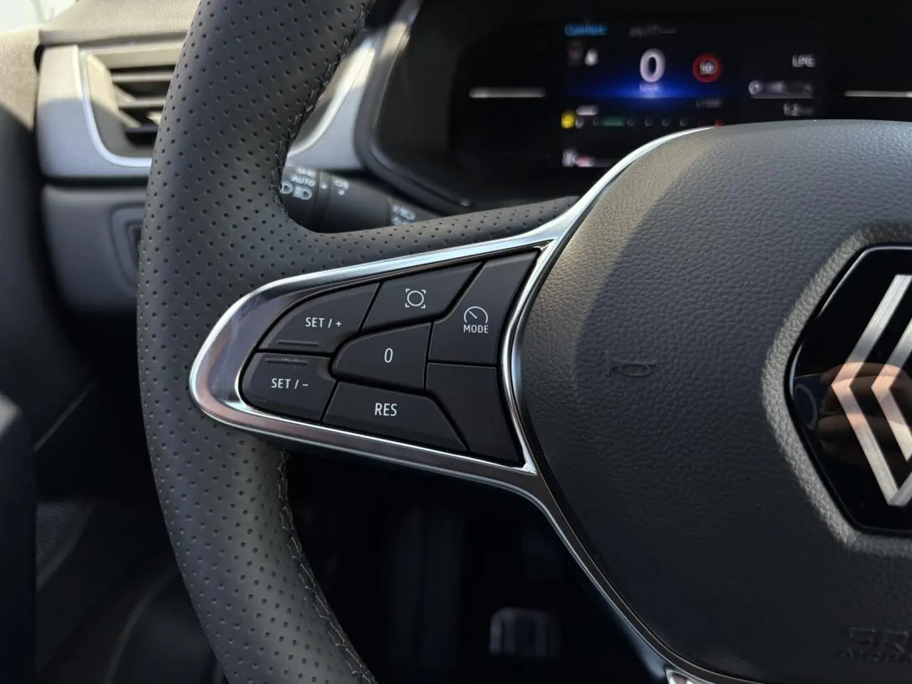 Gros plan sur le volant perforé du Renault Captur Gris Rafale 2025, avec commandes intégrées au côté gauche.