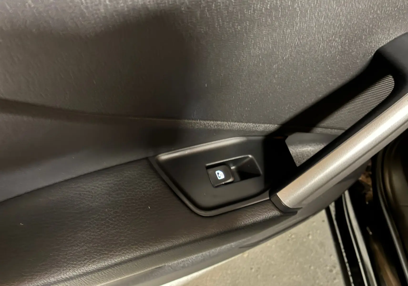 Bouton de commande de lève-vitre sur la porte intérieure côté gauche d'un Audi Q2 noir 2023 finition S-Line.