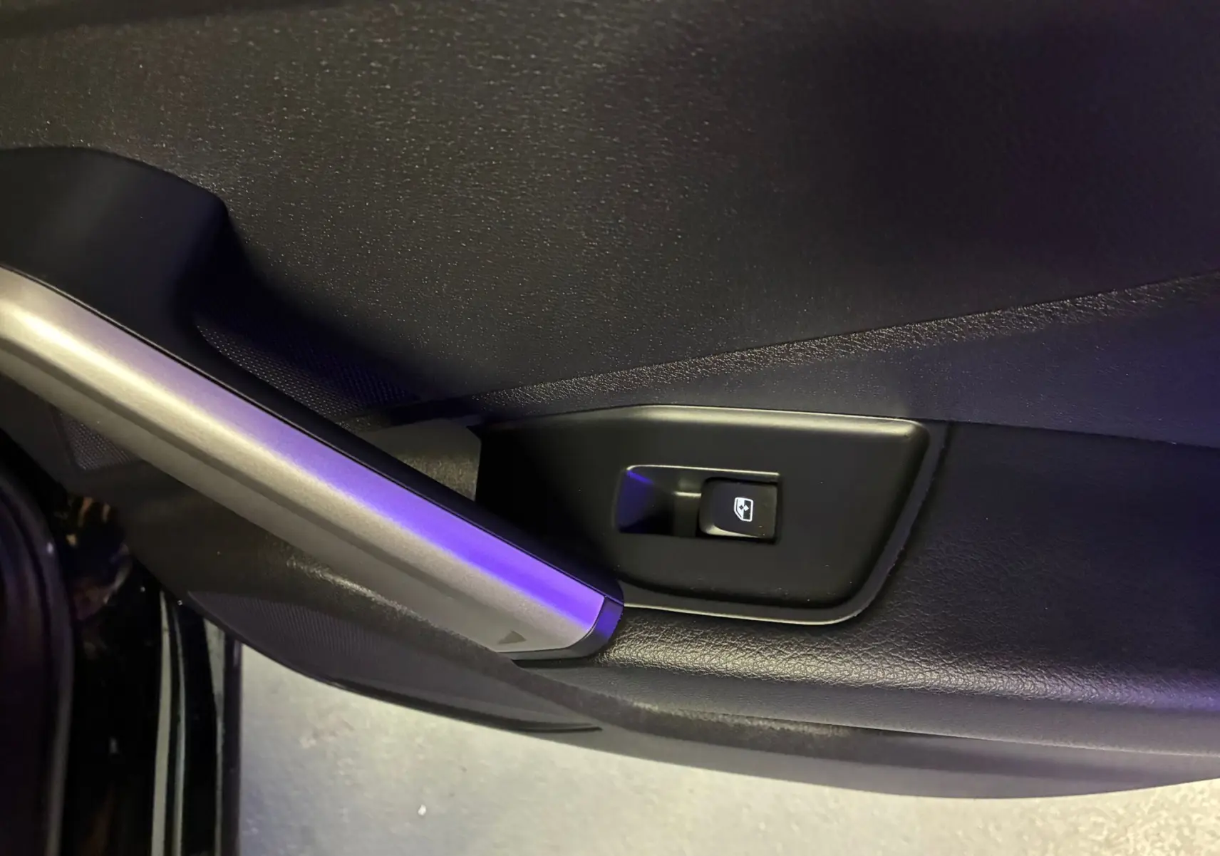Bouton de commande de lève-vitre sur la porte intérieure côté gauche d'un Audi Q2 noir 2023 finition S-Line.