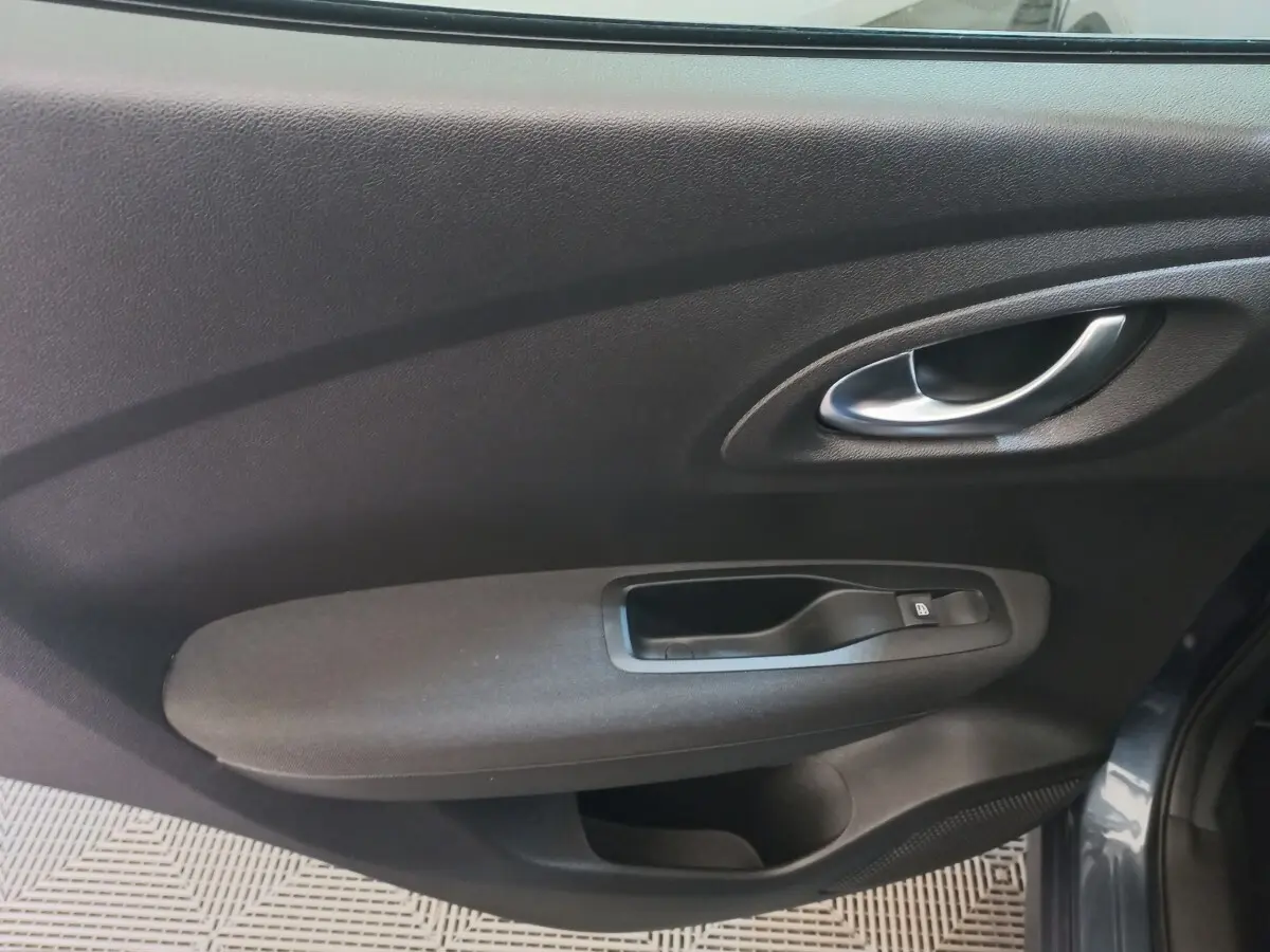 Intérieur côté gauche de la porte avant gris foncé du Renault Kadjar Business 2022 avec poignée et commande de vitre électrique.
