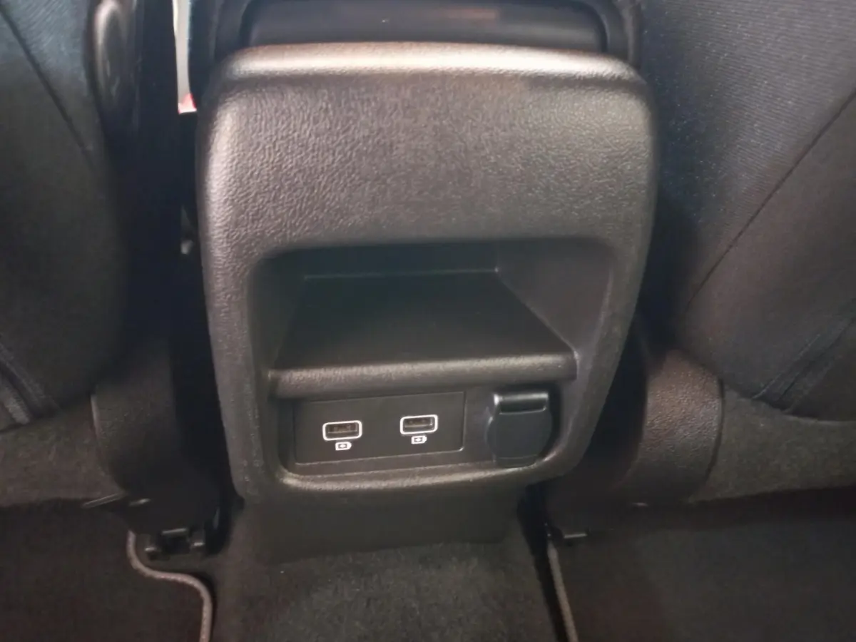 Prise USB double et prise 12V noire vue de près à l'arrière des sièges noirs du Renault Kadjar gris foncé.