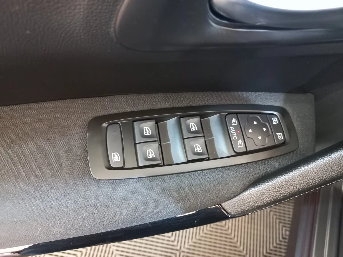 Gros plan sur les commandes électriques des vitres et rétroviseurs côté conducteur d’un Renault Kadjar gris foncé.