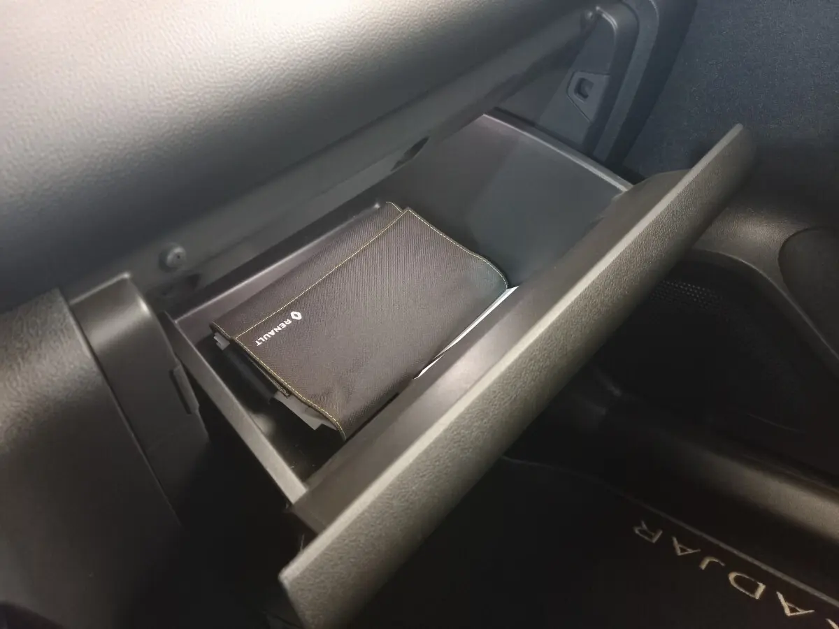 Gant de boîte à gants ouvert côté passager dans un Renault Kadjar gris foncé, avec pochette Renault visible.