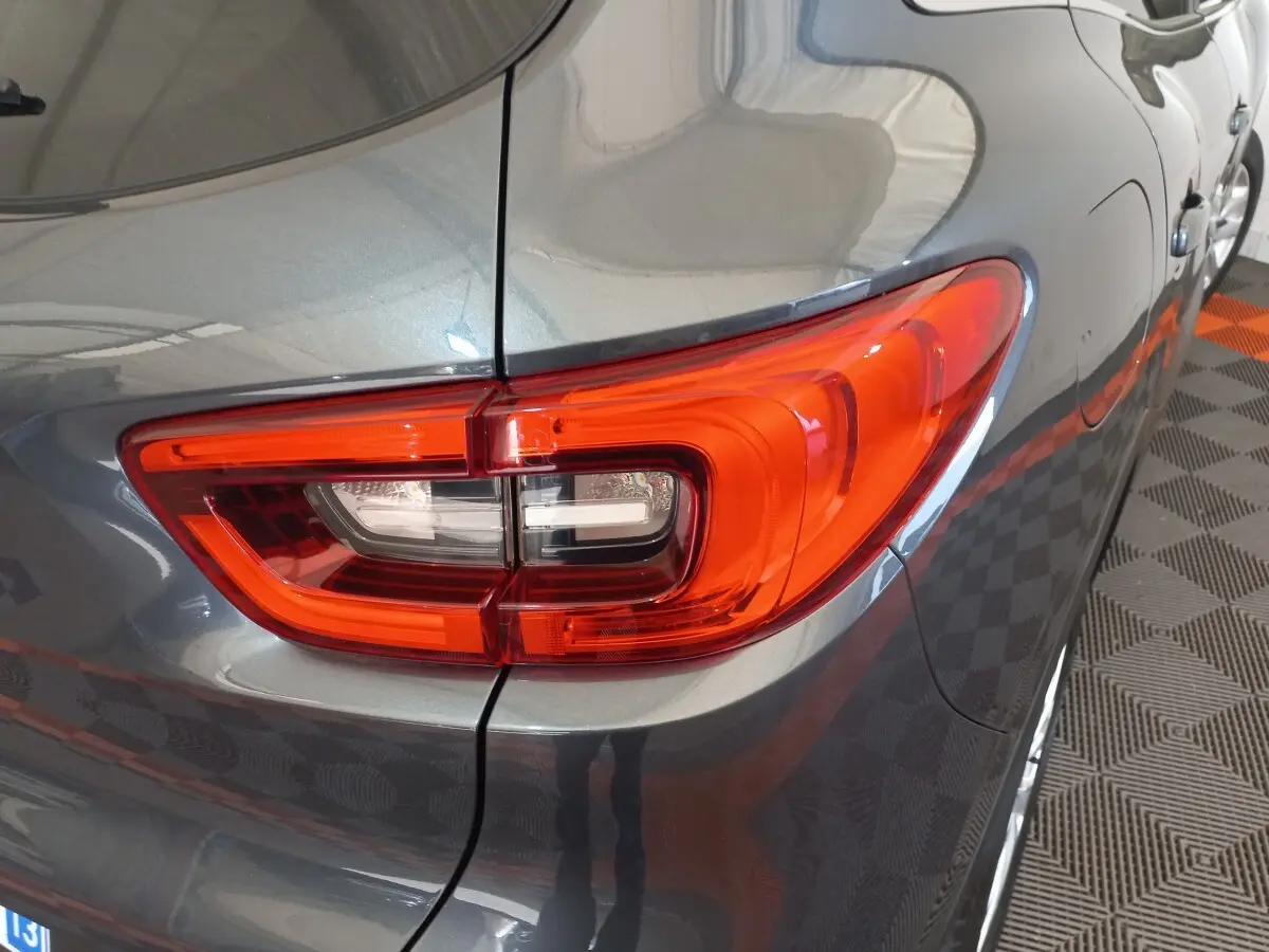 Gros plan sur le feu arrière droit rouge du Renault Kadjar gris foncé, avec partie latérale et reflet au sol.