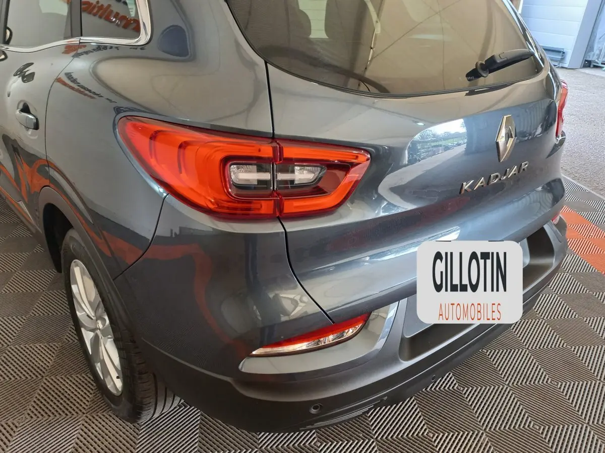 Vue 3/4 arrière droite d’un Renault Kadjar gris foncé avec feux arrière LED et logo visible sur un sol damier.