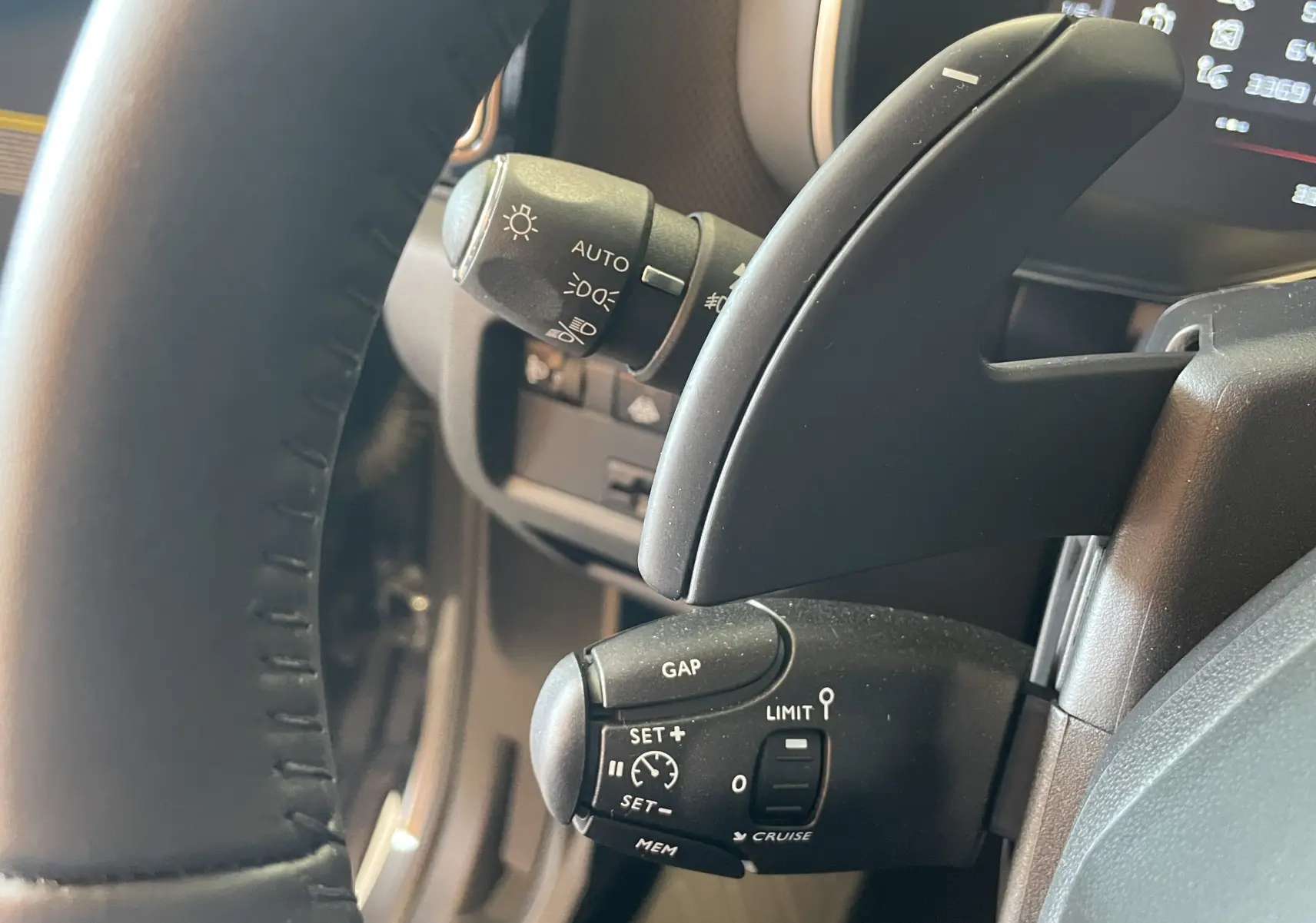 Gros plan sur les commandes au volant du Citroën C5 Aircross hybride gris platinium, avec régulateur de vitesse et éclairage automatique.