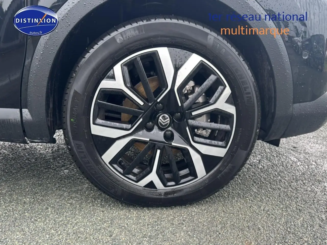 Gros plan sur la roue avant droite noire de la Citroën C4 1.2 hybride 2025 avec jante alu bicolore.