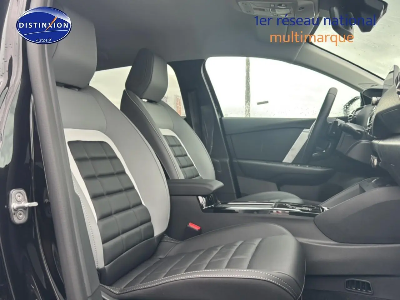 Intérieur de la Citroën C4 1.2 hybride 2025, vue côté gauche sur sièges cuir bicolores noir et gris avec accoudoirs.