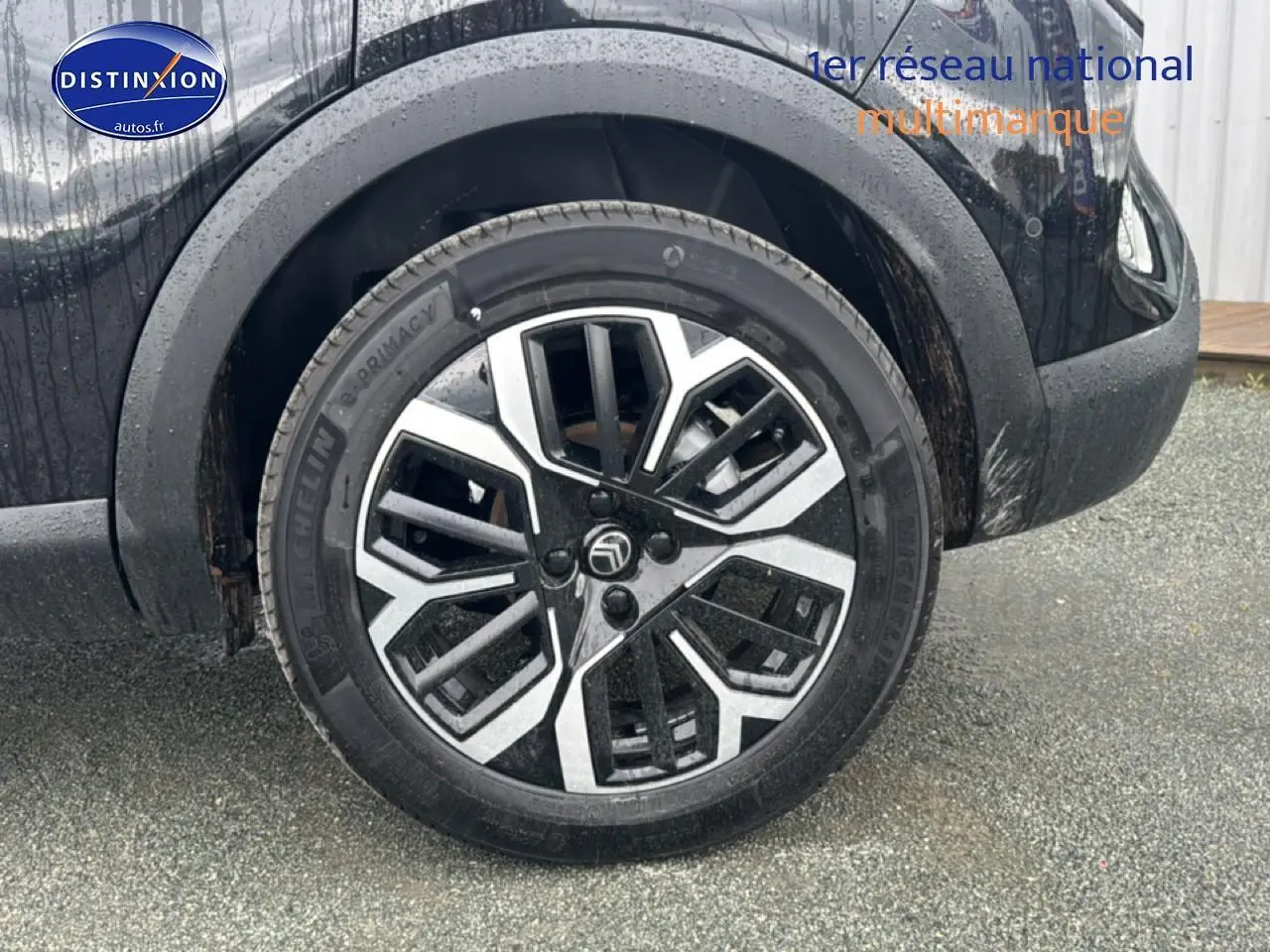 Gros plan sur la roue avant droite noire d'une Citroën C4 1.2 hybride 2025 avec jante alu bicolore.