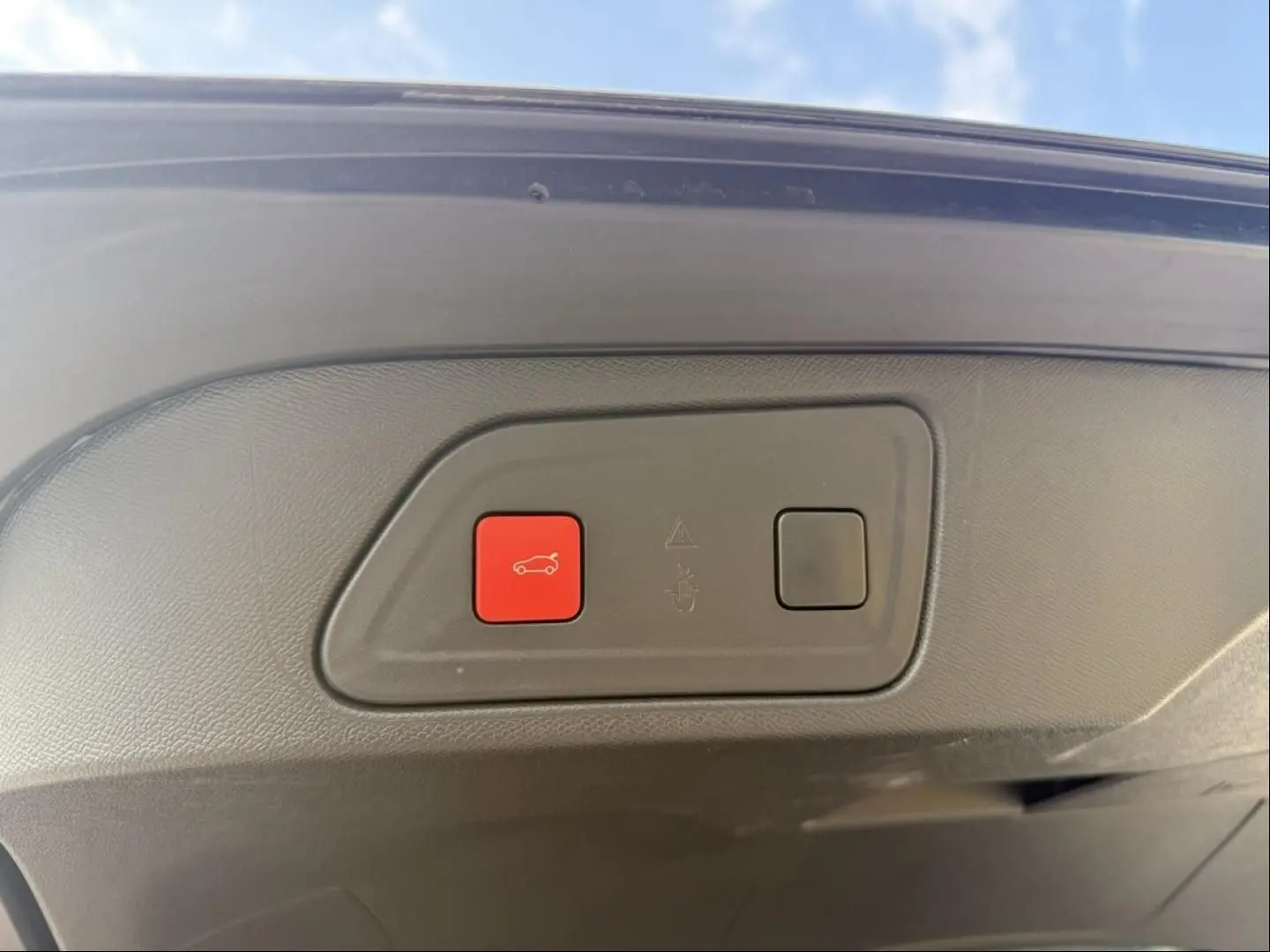 Bouton rouge d'ouverture électrique du coffre sur la partie intérieure du hayon d'un Citroën C5 Aircross noir métal 2024.
